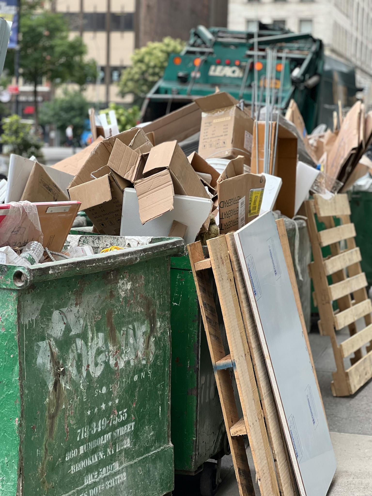 Piled cardboard boxes and waste in a city dumpster highlight urban recycling.